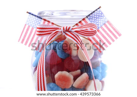 Happy Fourth of July patriotic jar of red, white and blue candy with flags on a white background. 