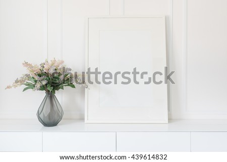 glass vase of flower with white picture frame on white table