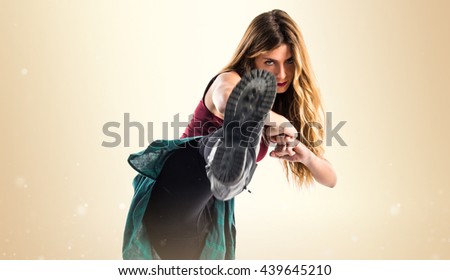 Young urban woman dancing over ocher background