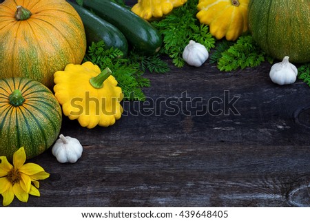 Fresh vegetables, pumpkin, zuchinni and herbs on wooden background, board frame and top view