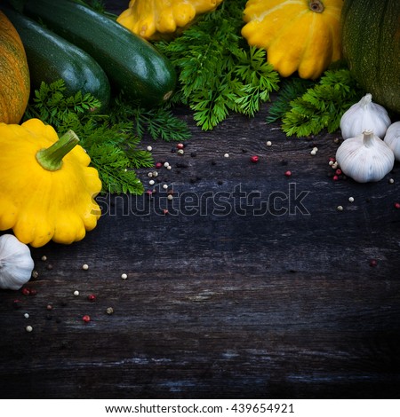 Fresh vegetables, pumpkin, zuchinni and herbs on wooden background, board frame and top view