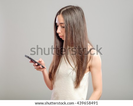 Attractive girl using her smartphone for texting isolated over gray background