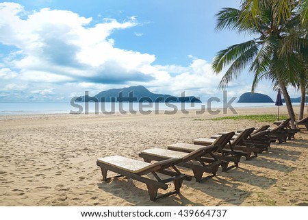 Beach chairs and coconut palm tree at the tropical beach. Pranburi, Thailand.