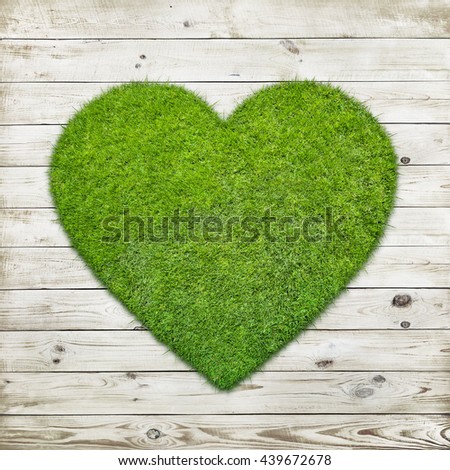 Heart shape of green grass over wood background