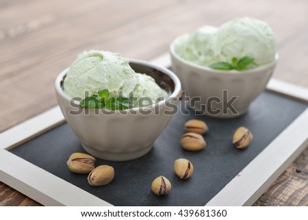Pistachio ice cream with mint and fresh pistachio on wooden background