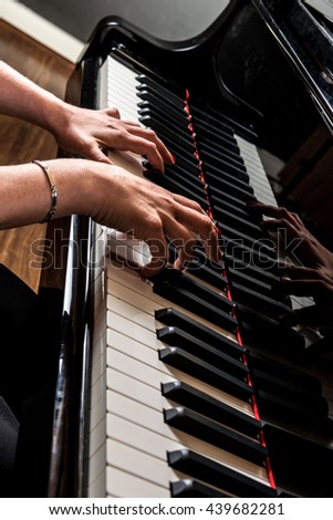 hands of a pianist playing on the keyboard of a grand piano