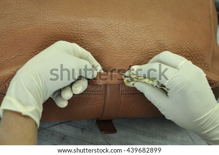 Leather Bag Cleaning and Moisturizing in Leather Factory. A leather factory worker removes stains and soil as well as to replenish vital oils and restore color. Royalty-Free Stock Photo #439682899