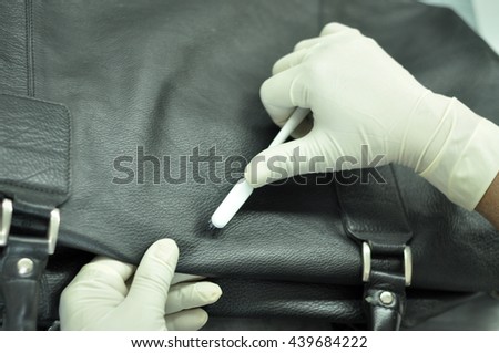 Leather Bag Cleaning in Leather Factory. A man cleaning a black leather bag with a brush to remove spots on it. Royalty-Free Stock Photo #439684222