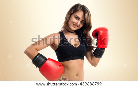Young girl with boxing gloves over ocher background