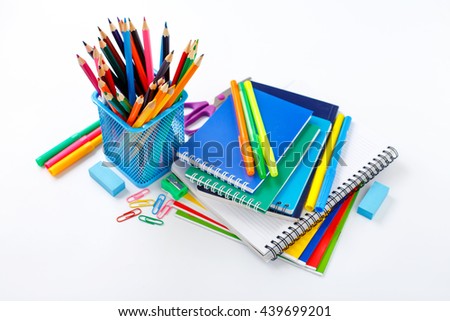 Back to school concept. Notebook and copybook stack with metal holder pencils, pens, paper clips, sharpener and eraser on a white background