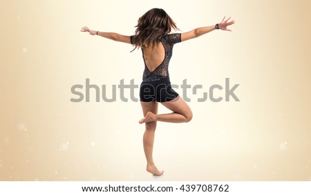 Young girl doing classical dance over ocher background