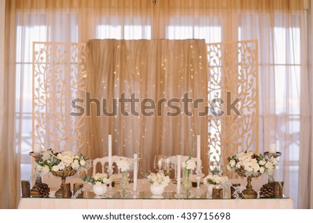 table setting at winter wedding reception, floral composition, candles and cones, lights on the background
