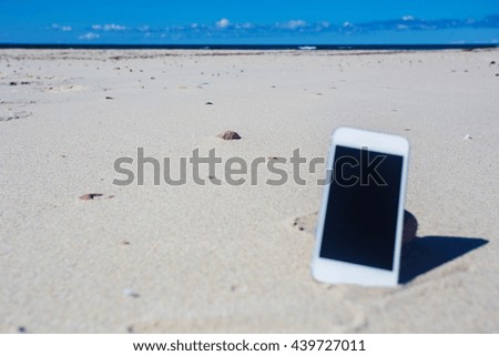 White smartphone on the beach. Gadget in sand.