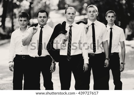 A black and white picture of groomsmen and groom posing in the park