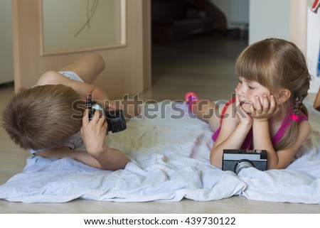 Little boy taking a picture of a little girl