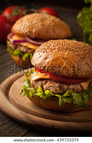 Home made hamburger with beef, onion, tomato, lettuce and cheese. Fresh burger closeup on wooden rustic table with potato fries and chips.