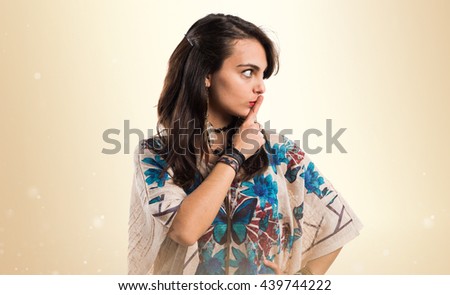 Young girl making silence gesture over ocher background