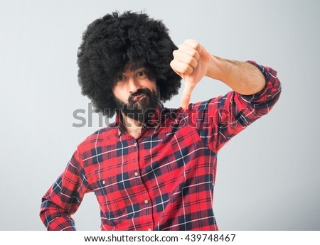 Afro man doing bad signal over grey background