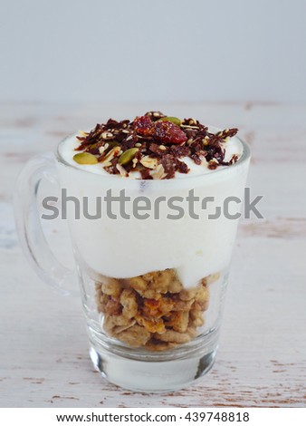 Yogurt with muesli and chocolate cereal on old rustic wooden table. Closeup Detail. Copy space.