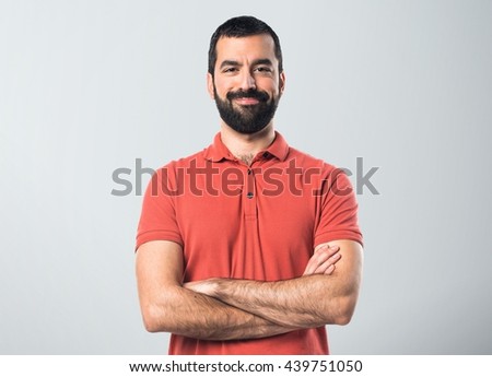 Man wearing red polo shirt with his arms crossed over grey background
