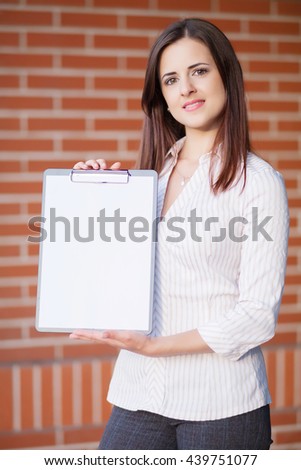 Business woman showing blank clipboard at her office 
