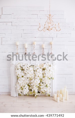 Elegant white fireplace full of flowers instead of fire. Elegant room