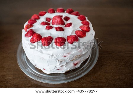 Delicious cake with cream and strawberries on the wooden table