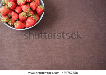 Pile of juicy ripe organic fresh strawberries in a large blue bowl. Dark background. Empty space