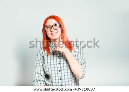 Portrait of girl shows a finger up, like, red-haired with glasses, isolated on a gray background