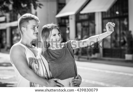 portrait of a young attractive tourist couple using a smartphone to take a selfie picture of themselves on holiday