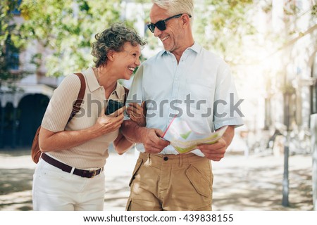 Retired couple walking around the town with a map. Smiling mature man and woman roaming around the city. Royalty-Free Stock Photo #439838155