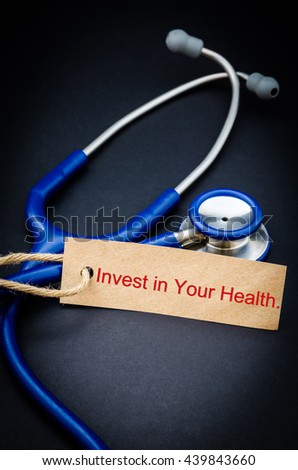 Invest in your health word in paper tag with stethoscope on black background - health concept. Medical conceptual