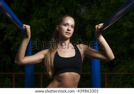Young and beautiful female has a rest from exercises on horizontal bars