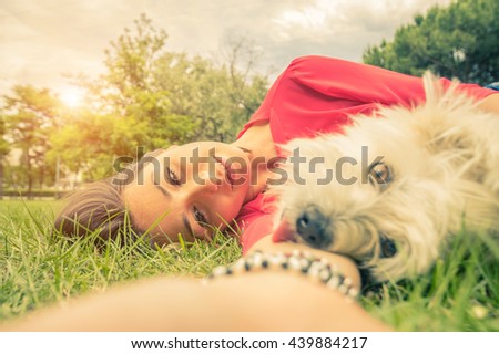 Young girl taking a selfie with her dog lying on the grass at the park