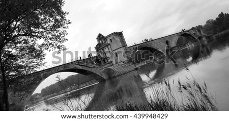 Pont Saint-Benezet. Famous half-ruined medieval bridge of Avignon (France) at sunset. Silhouettes of people on the bridge. Black and white photo.