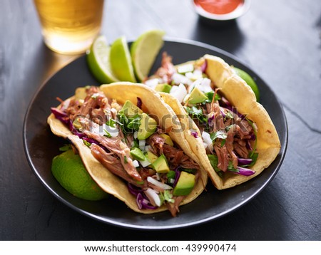 plate of mexican carnita tacos with beer in background