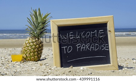Welcome to paradise written on a chalckboard at the beach                     