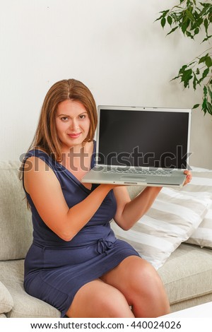 Picture of pretty businesswoman with red hair working on laptop computer at home. Beautiful woman holding computer with blank screen.