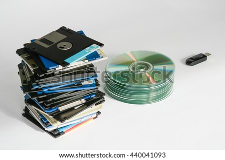Pile of floppy disks, cd-roms, external hard drive and pen drive over white like a digital revolution evolution