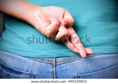 Close up of crossed fingers behind a woman's back Royalty-Free Stock Photo #440104852