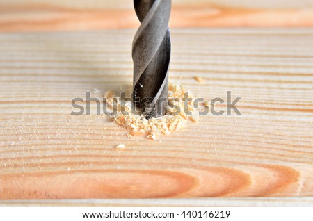 Steel boer drill a hole in a wooden board. Variety of carpentry tools and  locksmith instruments close-up. Joinery work. Royalty-Free Stock Photo #440146219