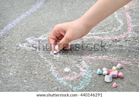Children's hand draws with chalk on the pavement. Creative leisure.
