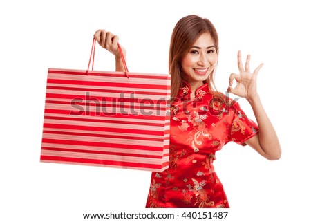 Asian girl in chinese cheongsam dress with shopping bag on gray background