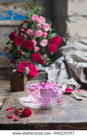 pink tea of the petals of a tea rose in a glass Cup on a wooden table. textured background in rustic style. selective focus
