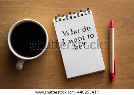 Who do I want to be? A question in handwriting on a notebook with cup of coffee