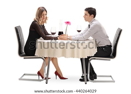 Young man apologizing to his girlfriend seated on a date isolated on white background