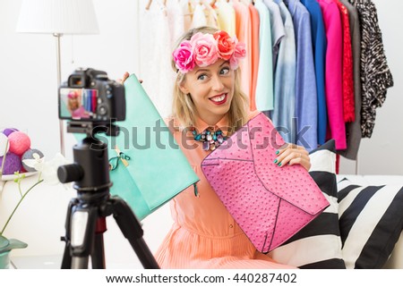 Fashion blogger taking picture and holding two clutch bags 