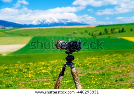 Camera on a tripod in the beautiful landscape of spring snow mountains