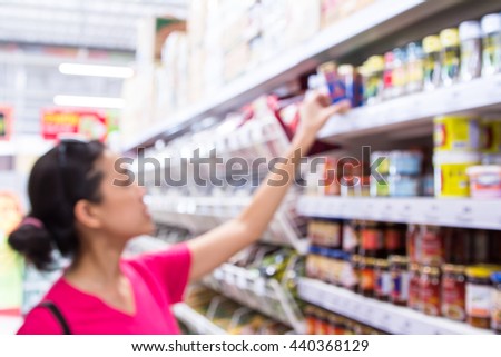 Blurred image of a woman with a shopping in the supermarket store.