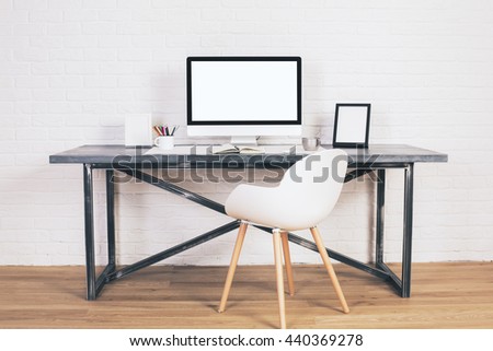 Front view of white chair and designer desk with blank laptop and picture frame on wooden floor and brick background. Mock up